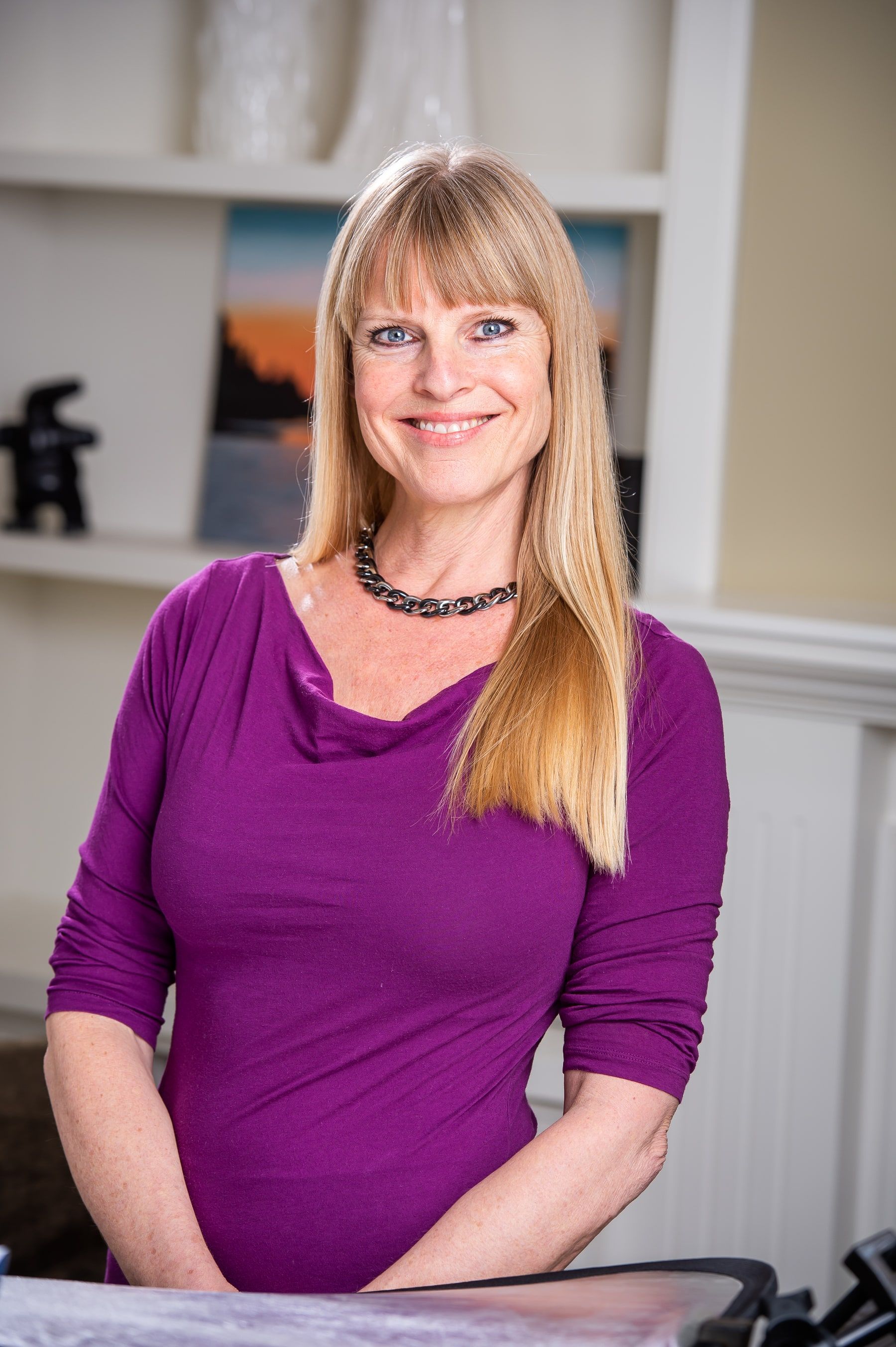 Deanna Hansen standing in her studio, smiling, in a magenta top